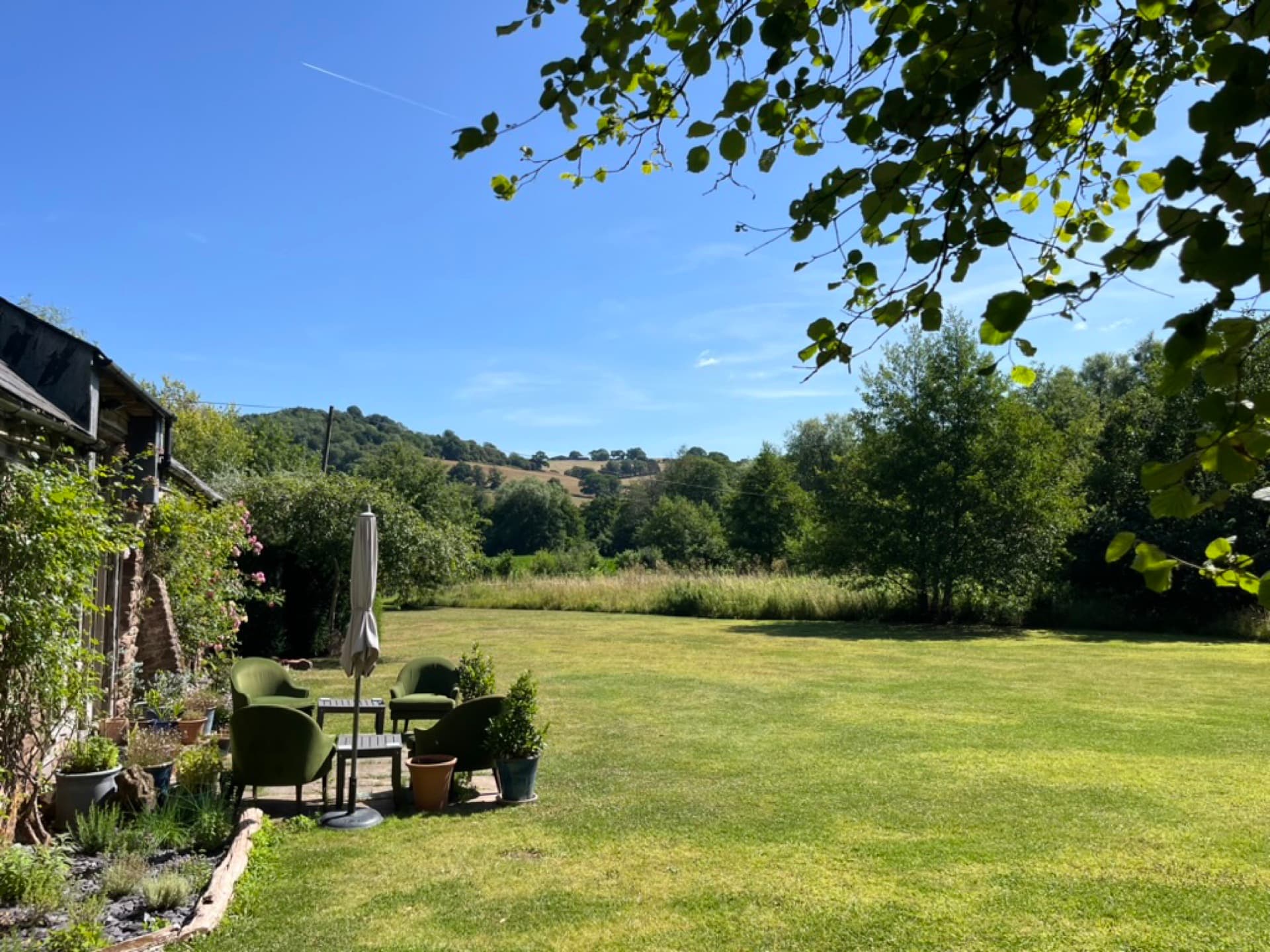 Two armchairs on the lawn with the Welsh hills and wildflower meadow behind