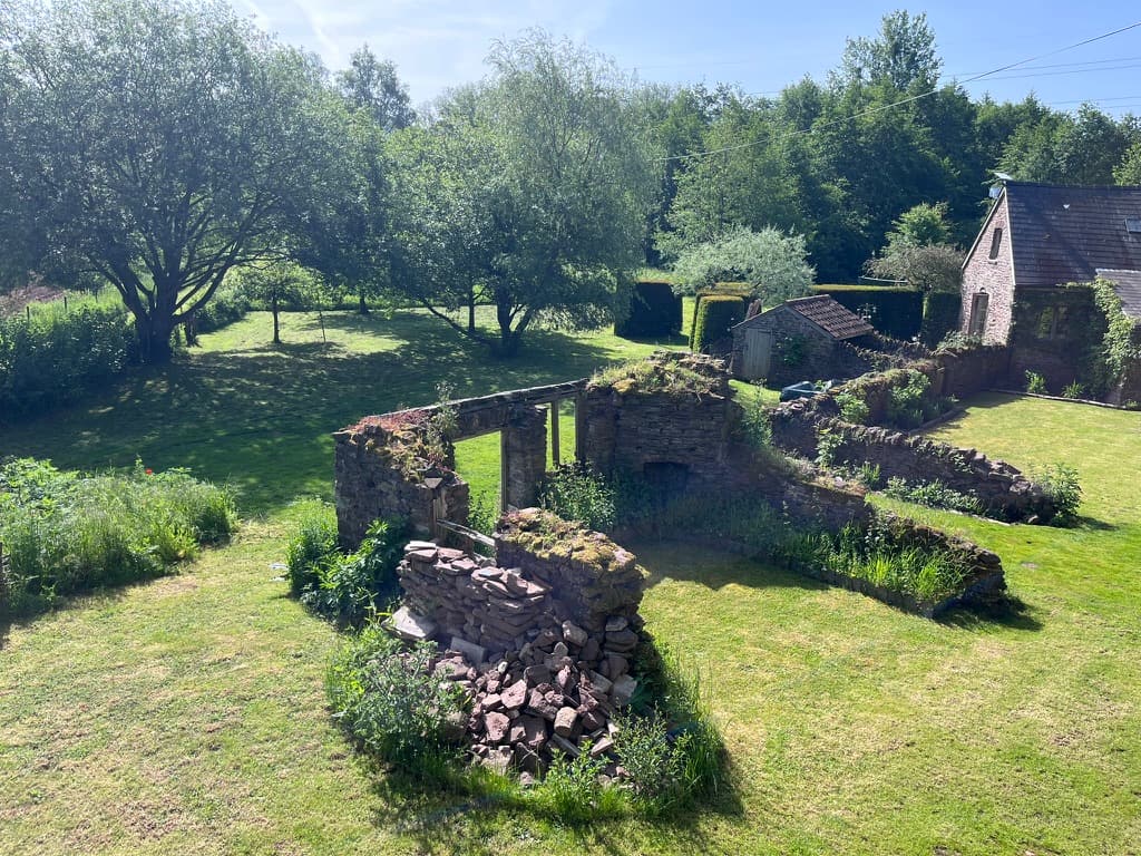 The old stone ruin and walled garden at Ruthlin, a riverside retreat in Monmouthshire, with the barn beyond
