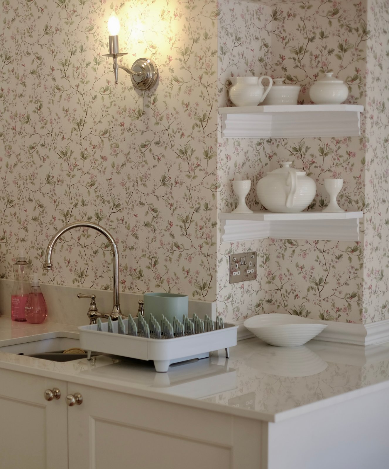 The kitchen at Ruthlin, with floral wallpaper and handmade white pottery